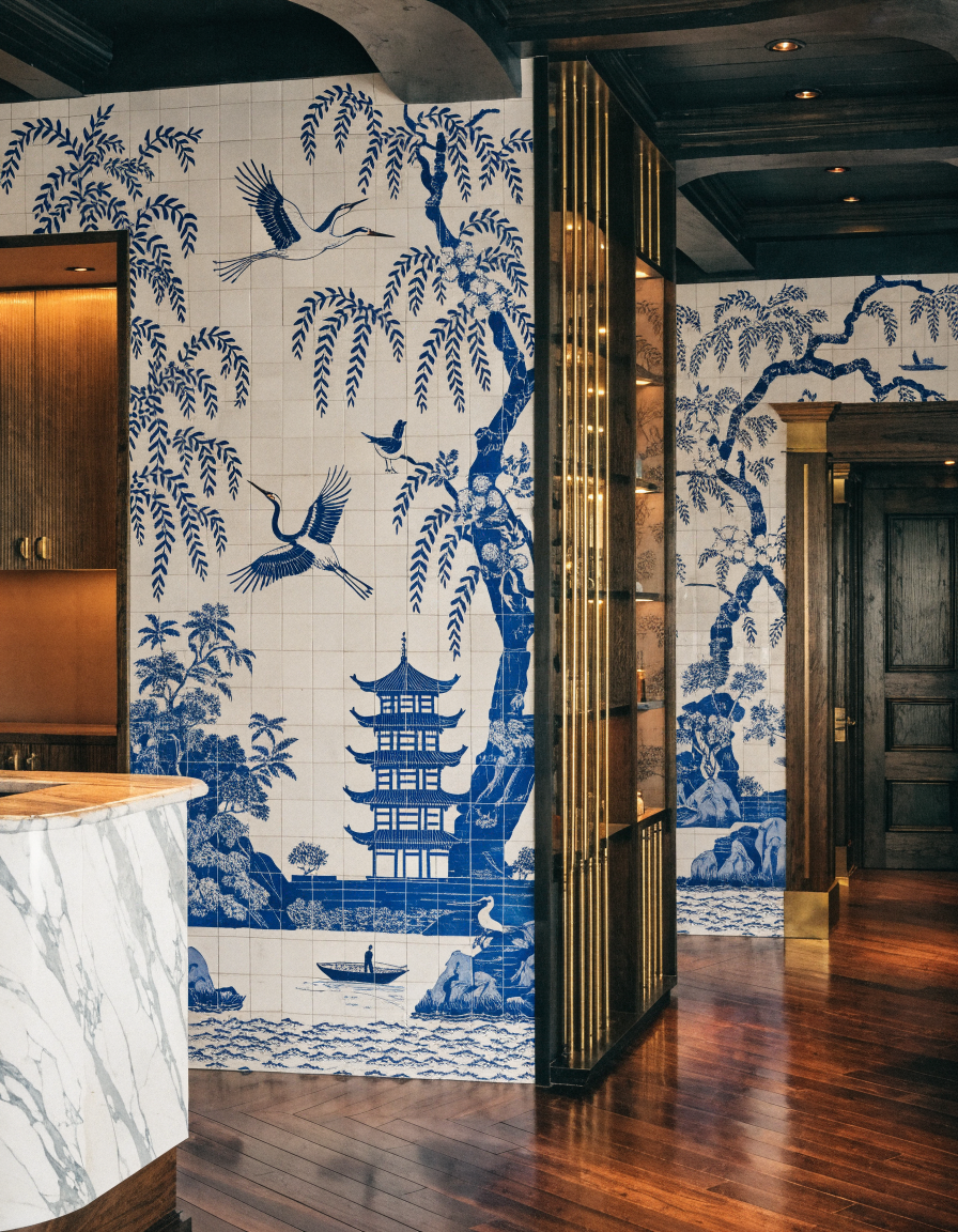 Parete reception rivestita in piastrelle di porcellana blu e bianco con decoro chinoiserie a pagoda, salici e uccelli